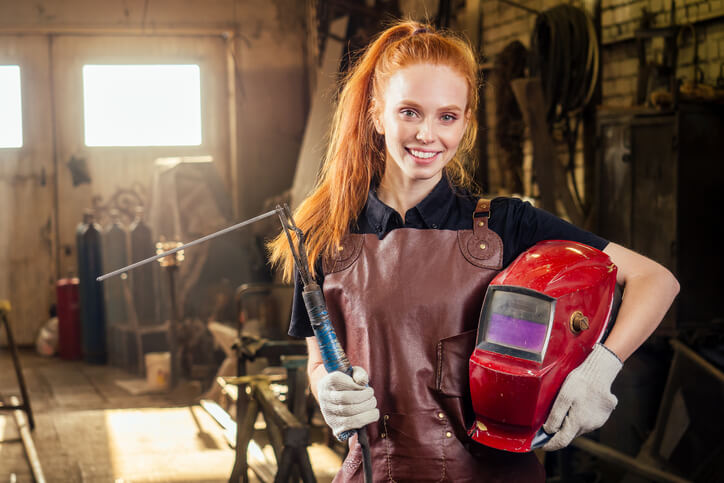 Student in welder training smiling and holding helmet