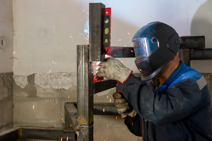 A professional welder taking measurements of a spiral staircase after welder training
