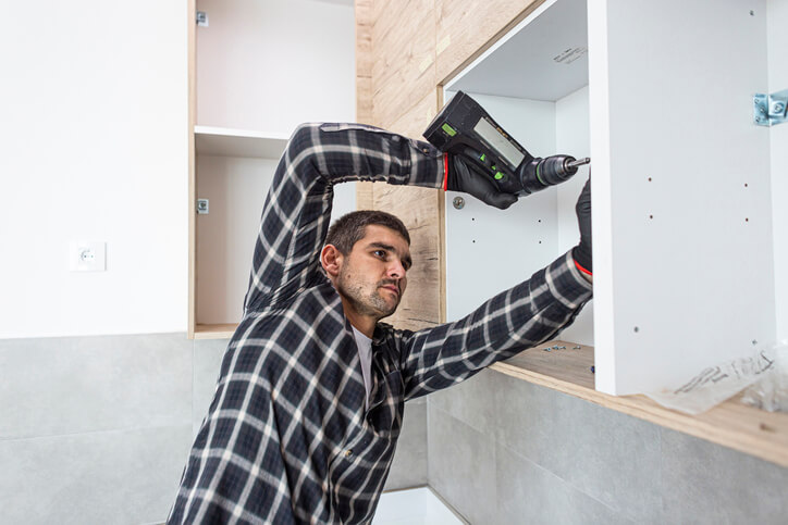 A cabinet maker assembling a kitchen cabinet after cabinet making training