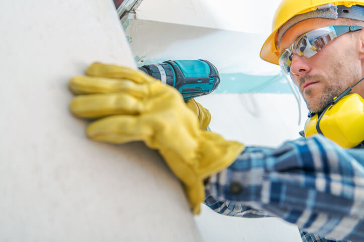 A male drywall installer in a building after home renovation training.