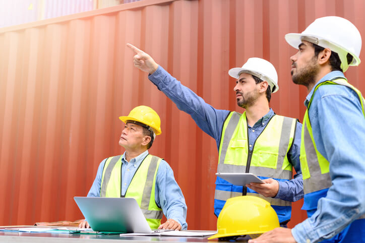 A logistics management training graduate working with colleagues outside of a warehouse.