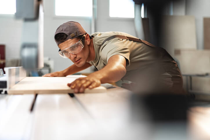 Male cabinet maker in protective gear working on a project after cabinet making training