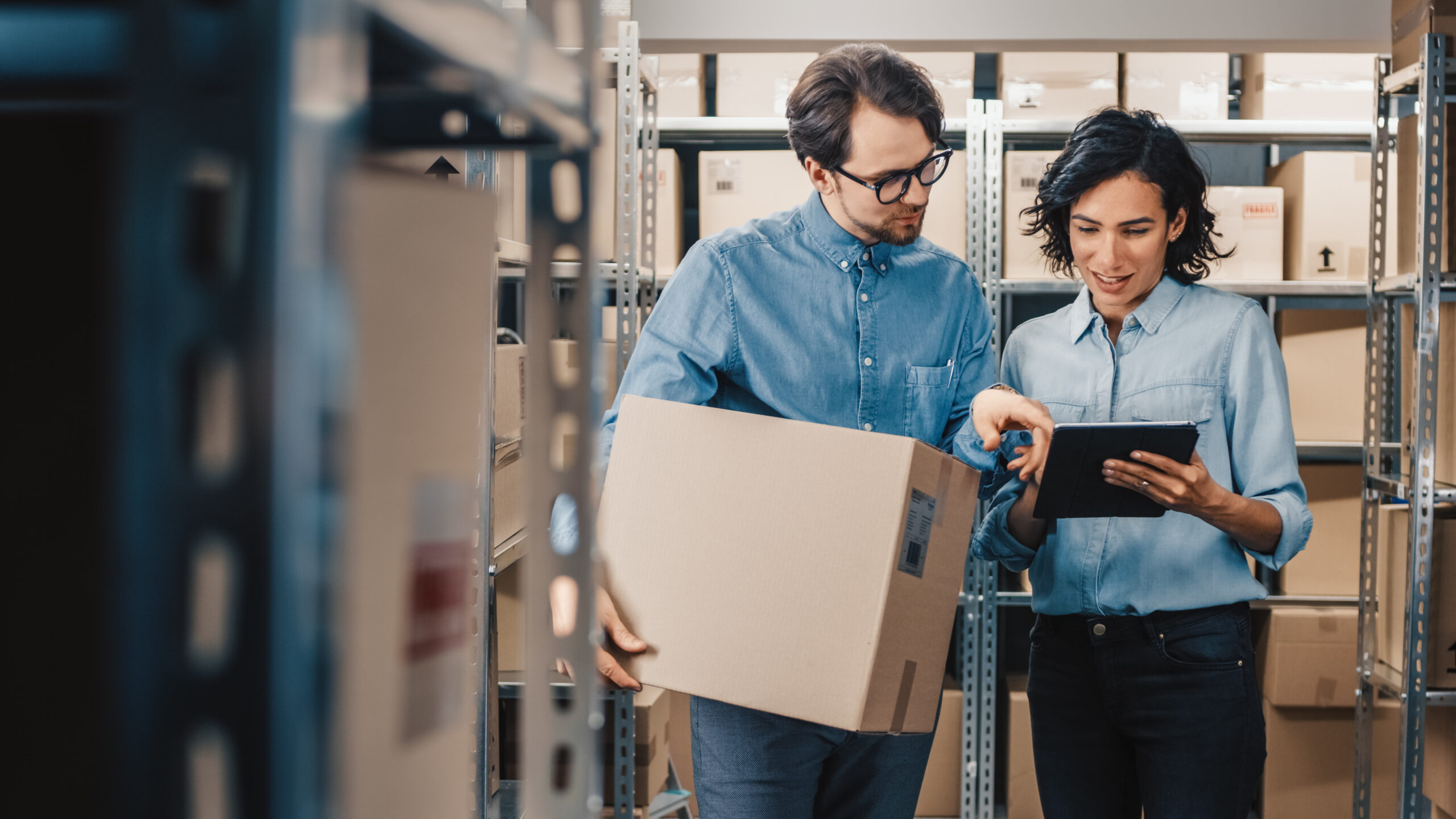 Female inventory manager shows digital tablet information to a worker