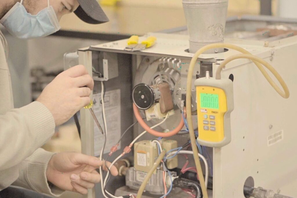 An HVAC technician working on an industrial furnace system after completing his HVAC technician training