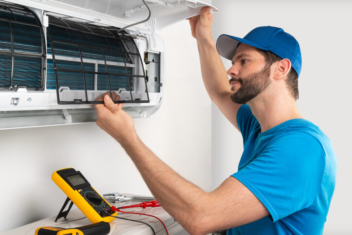 An HVAC training technician graduate replacing an air conditioner part.