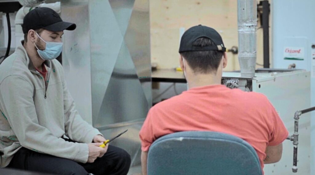 A male HVAC technician interacting with a customer after completing his HVAC technician training