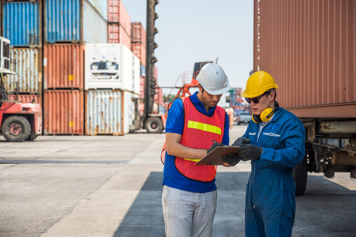 A logistics manager interacting with a truck driver at a warehouse after logistics management training